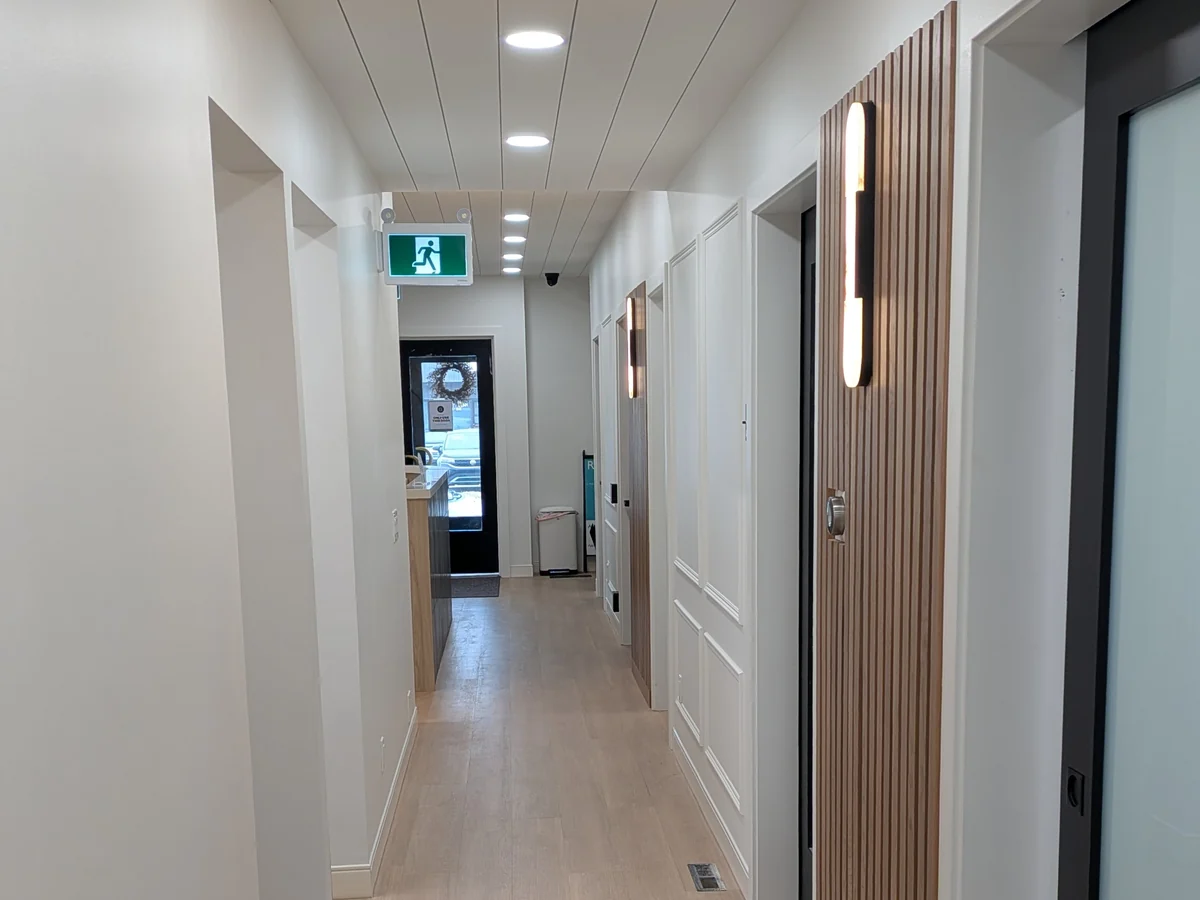 Renovated clinic hallway with wood wall panels and illuminated sconces